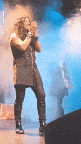 a man with curly hair is singing into a microphone on stage