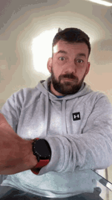 a man with a beard wears a grey under armour sweatshirt