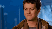 a man is smiling and looking at the camera while wearing a jacket .