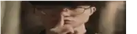 a close up of a person wearing glasses holding their finger to their mouth .