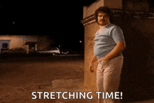 a man with a mustache is standing in front of a building and stretching his legs .
