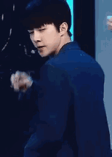 a young man in a blue suit is looking over his shoulder at the camera .