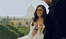 a woman wearing glasses is giving a thumbs up to a man in front of a building