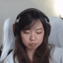 a woman wearing headphones is sitting in a chair and looking down .