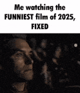 a man is sitting in a dark room watching a funny movie .
