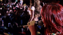 a woman with red hair singing into a microphone with rbd.gif written on the bottom