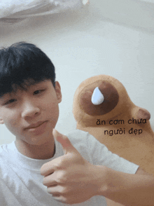 a young man giving a thumbs up next to a stuffed animal that says an cam chua người đẹp