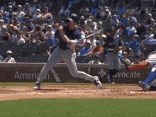 a baseball player swings his bat at a ball in front of an american advocate sign
