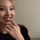 a close up of a woman 's face with a ring on her finger and smiling .