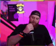a man singing into a microphone in front of a sign that says voodoo