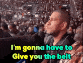 a man sitting in a stadium with the words i 'm gonna have to give you the belt