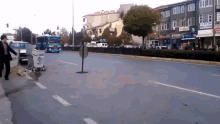 a man walking down a street with a trash can that says ' polis ' on the side