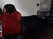 a red and black racer gaming chair sits in a dark room