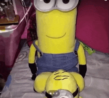a stuffed minion is sitting on a bed next to another minion