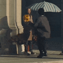 a man holding a striped umbrella walks down a sidewalk next to a woman