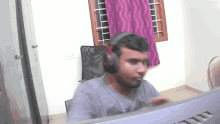 a man wearing headphones looks at a computer monitor