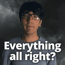 a man wearing glasses stands in front of a sign that says " everything all right "