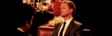 a man in a suit and tie is talking to another man with the words commeca ? written on the bottom .