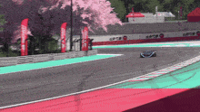 a race car is going down a track with a fence that says ' acura ' on it