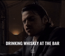 a man is drinking whiskey at a bar
