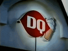 a red and white dq sign with a cup of ice cream on it