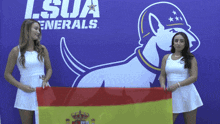 two women holding a spanish flag in front of a lsu generals sign