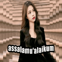a woman in a black dress stands in front of a sign that says assalamu'alaikum