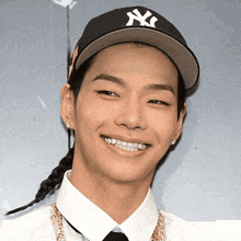 a young man wearing a ny yankees hat smiles