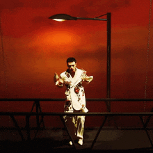 a man in a white suit with red flowers on it