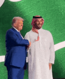 a man in a blue suit shakes hands with a man in a white dress