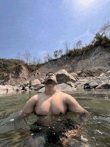 a man without a shirt is swimming in a river