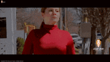 a woman wearing a red turtleneck is standing in front of a sign that says lillee blane