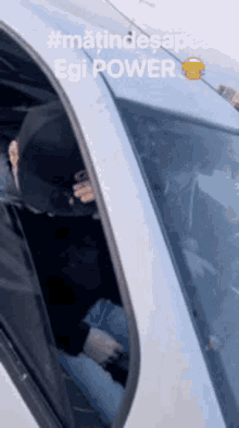a man wearing a black hat is sitting in a car with the words egi power on the roof