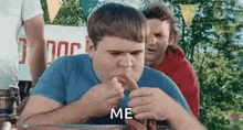 a man is eating a hot dog at a hot dog eating contest while another man watches .
