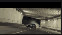 a car is driving through a tunnel with smoke coming out of the tires