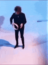 a man in a black suit is dancing with a tambourine in his hand