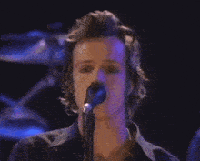 a man is singing into a microphone with a ring on his finger