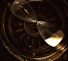 a close up of a hourglass with a clock in the background that says ' clock ' on it