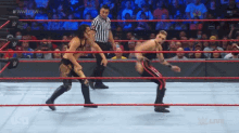 two wrestlers in a wrestling ring with a referee watching