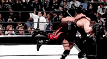 two wrestlers are fighting in a wrestling ring with a crowd watching .