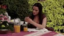 a woman is sitting at a table with a pitcher of orange juice