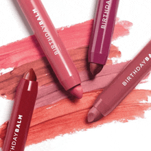 four different shades of birthday balm lipsticks on a white background