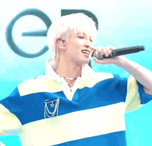 a man wearing a blue and yellow striped shirt is holding a microphone