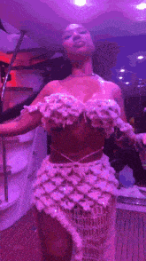 a woman in a white dress is dancing on a boat with purple lights behind her