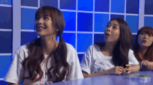 a group of girls are sitting at a table and one of them has a name tag that says ' a ' on it .