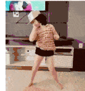 a little girl is dancing in a living room while wearing a hat .