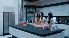 three women standing in a kitchen preparing food on a large island