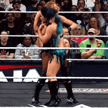 a woman with blue hair is wrestling another woman in a wrestling ring with a crowd watching