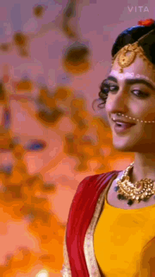a close up of a woman wearing a yellow top and a red saree .