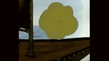 a large yellow object is floating in the air above a body of water .
